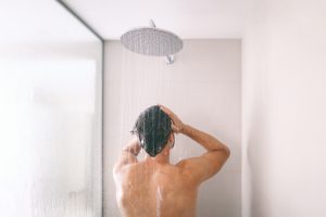 Man taking a shower washing hair with shampoo product under water falling from luxury rain shower head. Morning routine luxury hotel lifestyle guy showering. body care hygiene | Replacing a master bathtub with a luxury shower | Replacing a master bathtub with a luxury shower